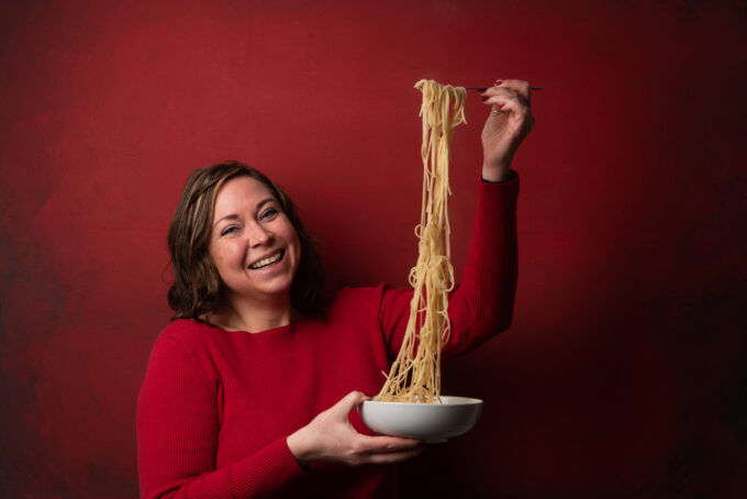 a woman holding a bowl of spaghetti