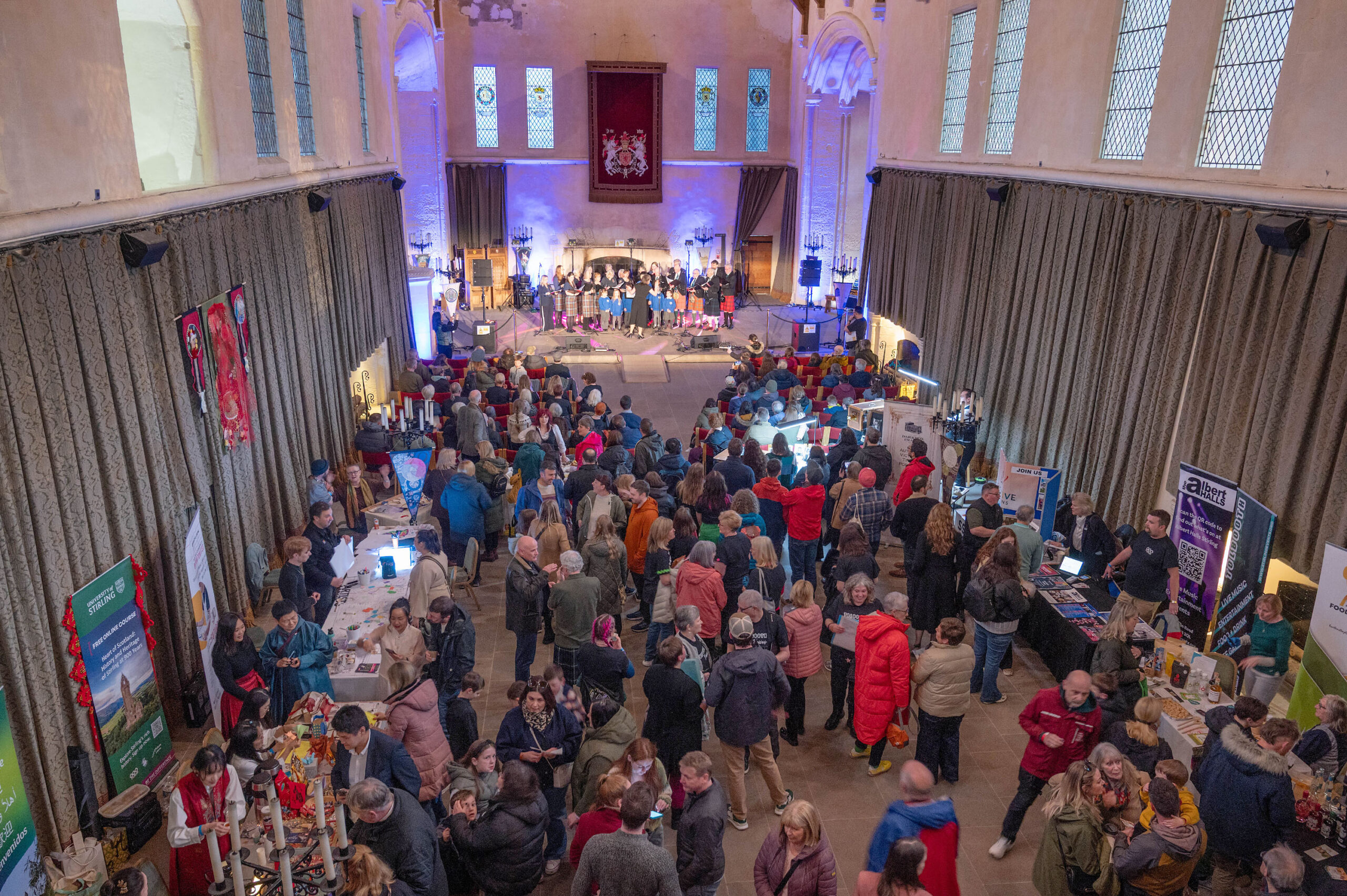 A hall full of people with information stands and a choir