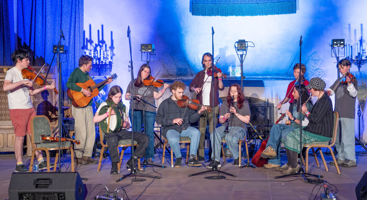 A group of musicians playing violin, guitar, flute and other instruments in a hall